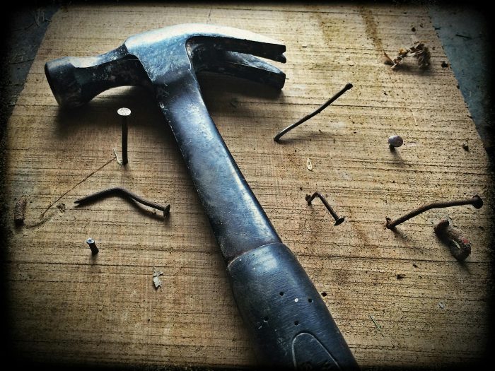 A hammer and nails on a wooden surface.