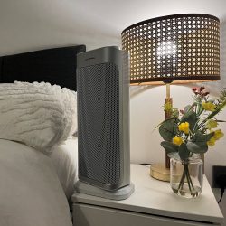 table top ceramic fan heater sitting in front of a lamp and flowers