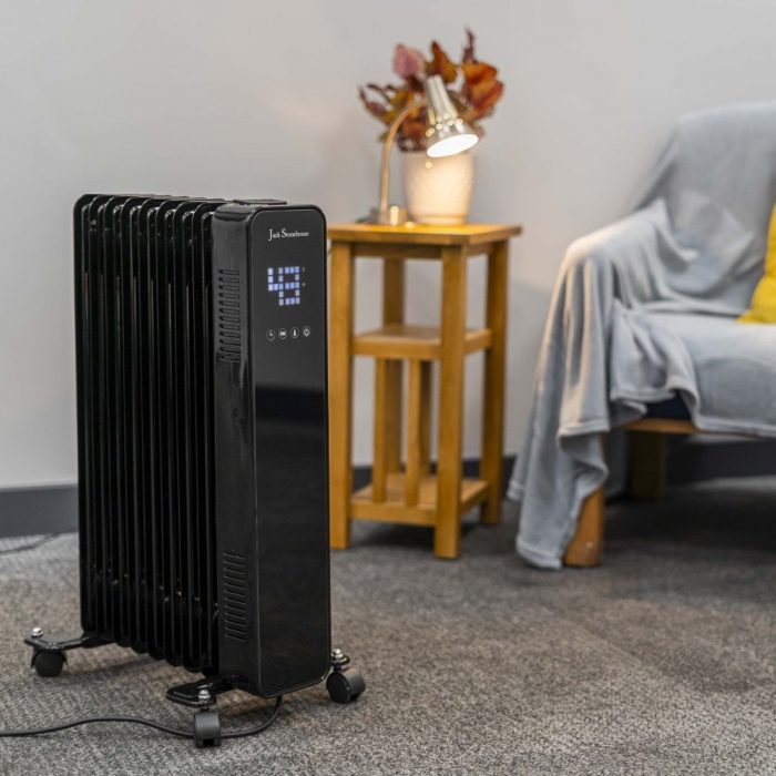 A black oil heater positioned on a soft carpeted floor, providing warmth to the surrounding area
