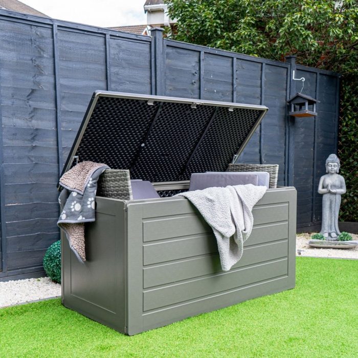 A large garden storage container with cushions and blankets inside.