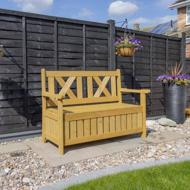 Wooden garden storage bench in a garden with flowers hanging overhead.